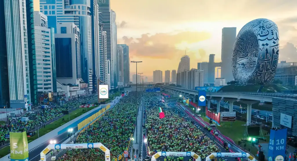 Aerial view of tens of thousands of runners filling Sheikh Zayed Road for the Dubai Run at sunrise, with the Museum of the Future and Dubai skyline behind — an event powered by Glow Power Rental